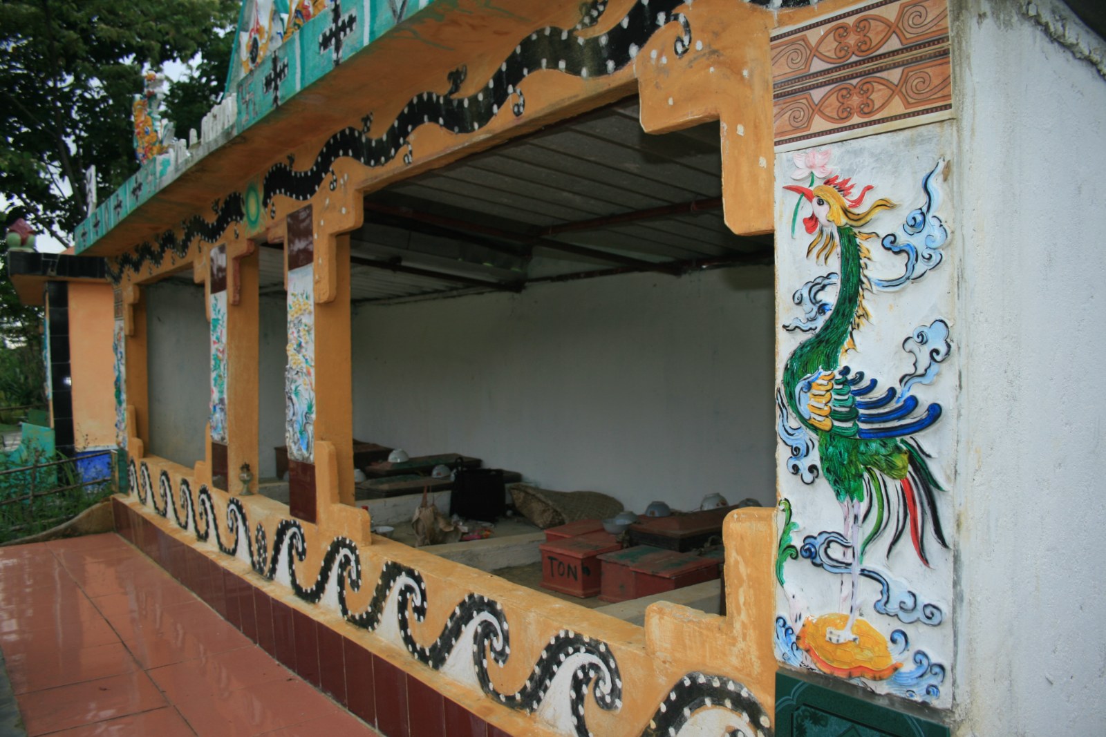 Painted tomb houses with carved posts and a peacock figure, in A Luoi