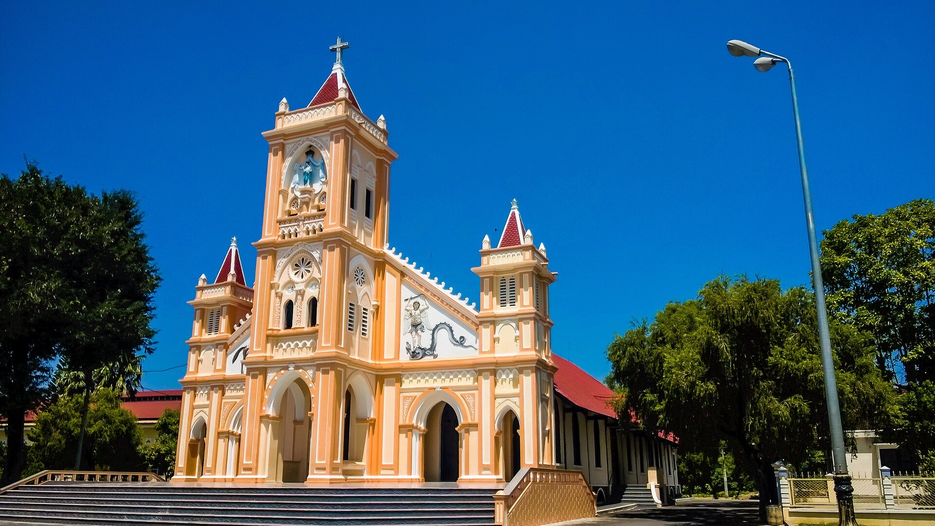 A yellow church with twin towers and a tall central façade against a blue sky