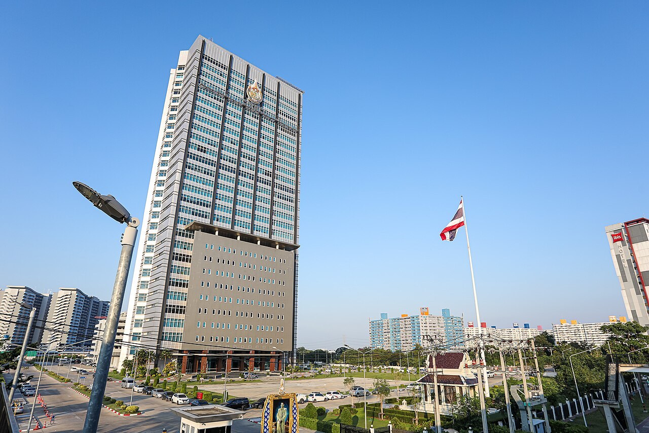 A tall office tower with a Thai flag on a pole in front of it