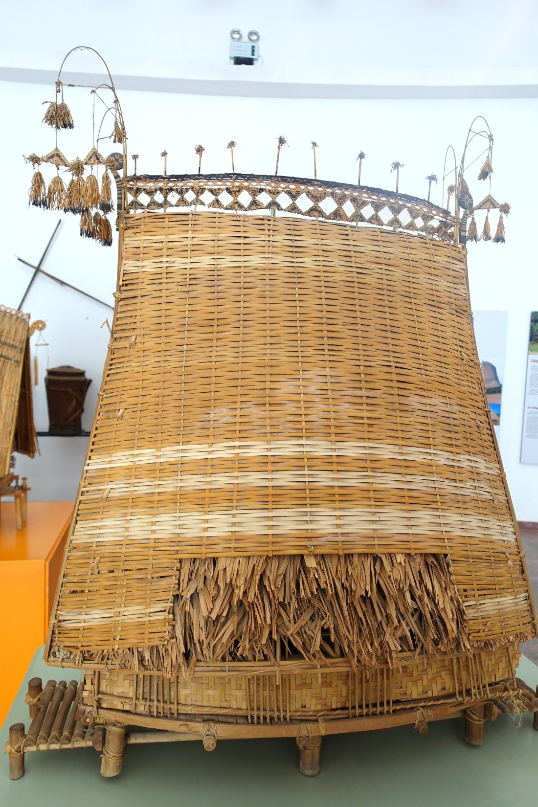 A model of a communal house with a tall thatched roof