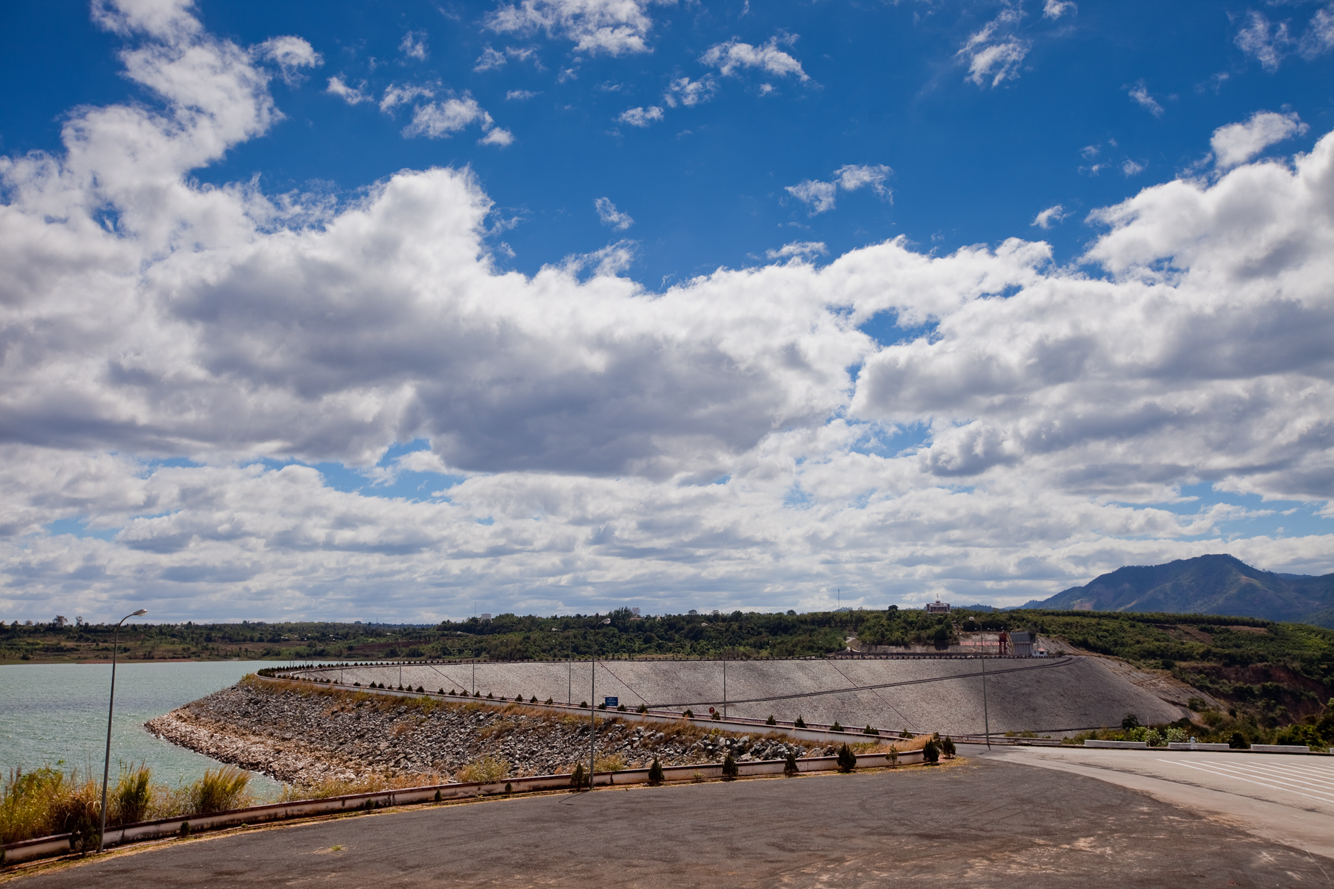 A long concrete dam across a river under a wide sky